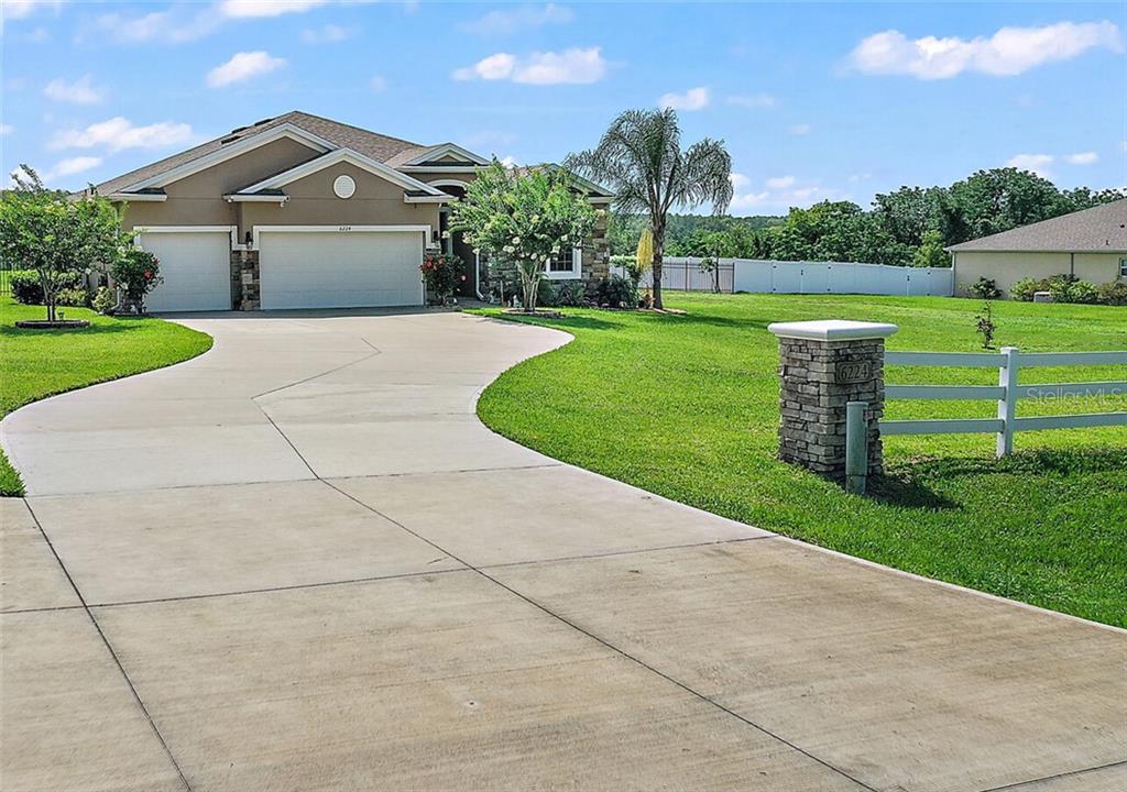 Curved driveway, gorgeous curb appeal with well-manicured plants, flowers, and a lovely lawn.