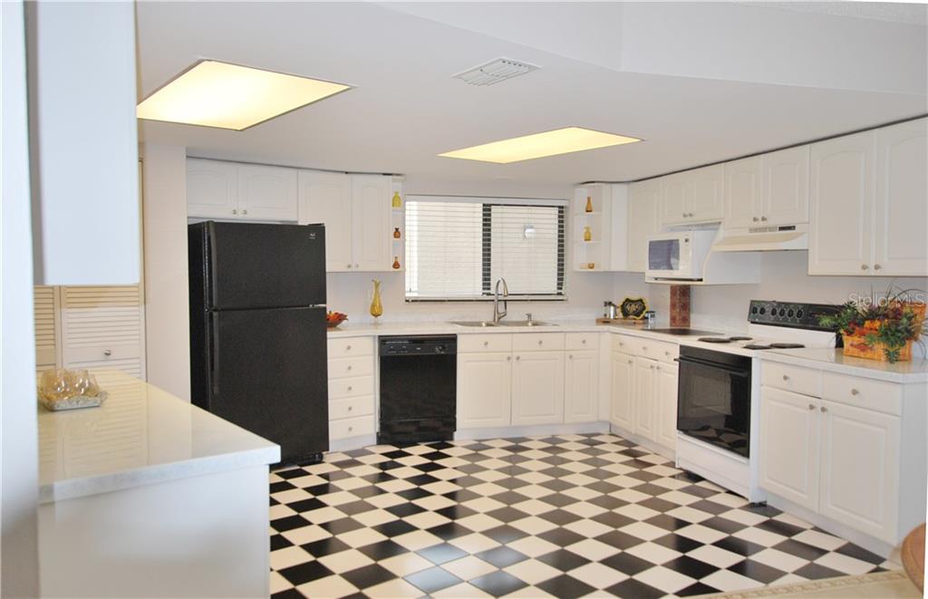 Expansive kitchen with loads of counter-space, resin counter-tops, and two windows, making it bright and cheery.