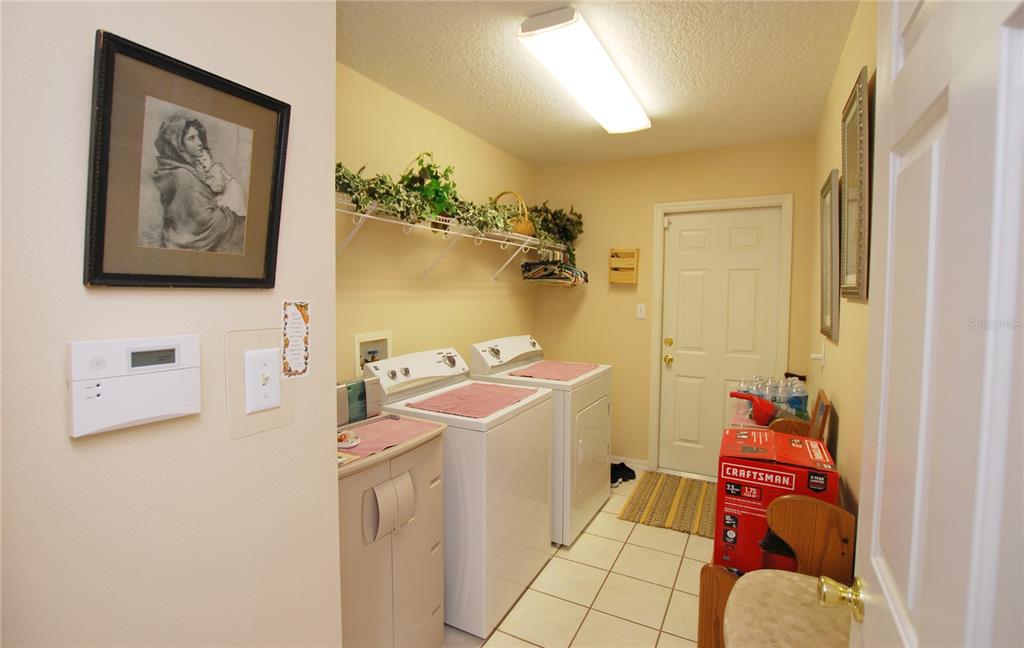 Wide and spacious laundry room with washer and dryer. It is accessed from hall and goes out to garage.