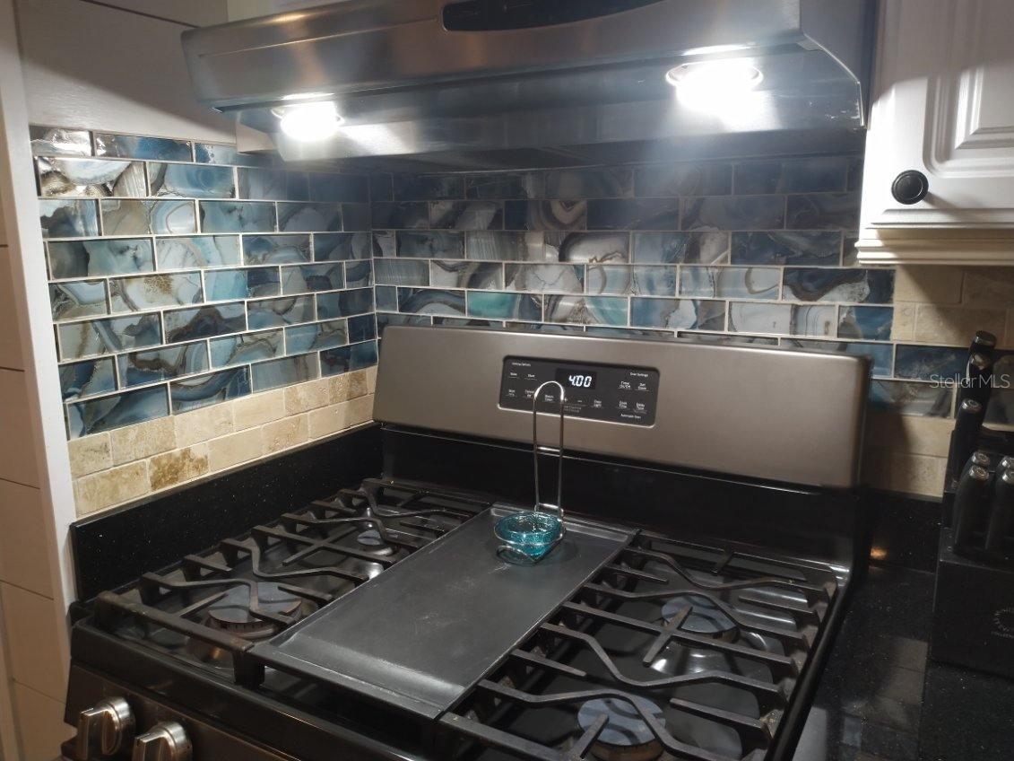 CLOSEUP OF TRAVERTINE MARBLE AND GLASS SUBWAY TILES BACKSPLASH BEHIND RANGE