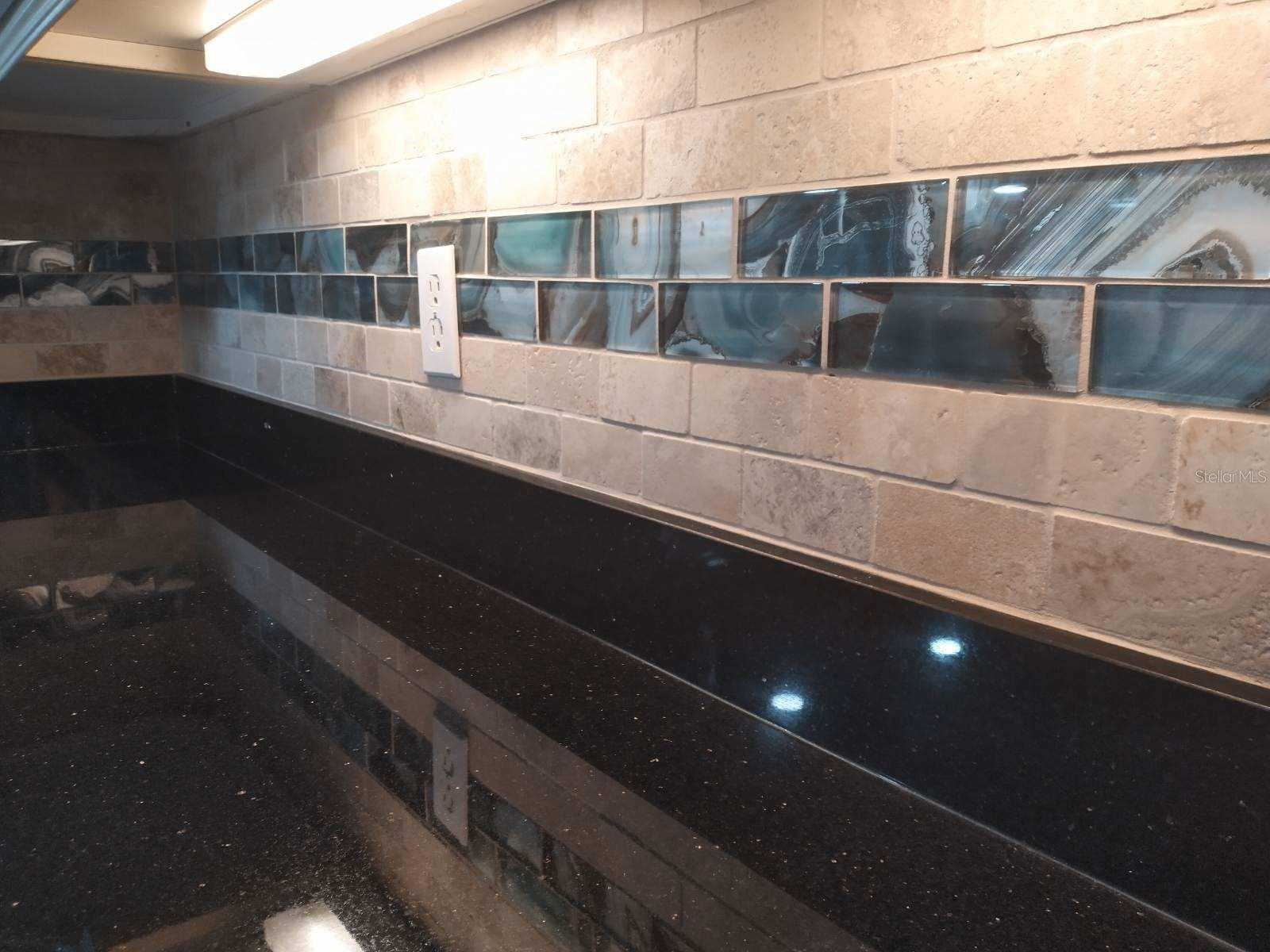 CLOSEUP OF TRAVERTINE MARBLE, AND GLASS SUBWAY TILES BACKSPLASH UNDER CABINETRY